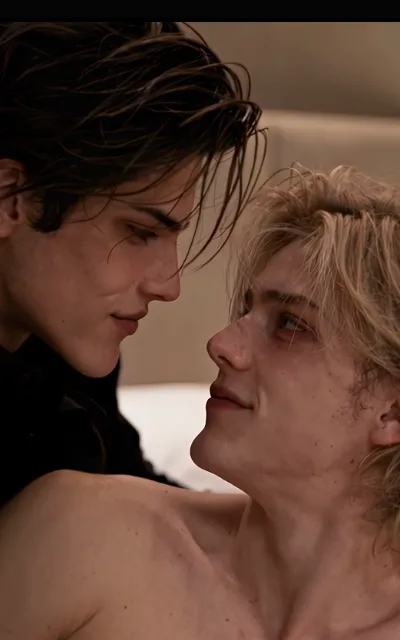 Nose to nose — a dark-haired man with a soft smile leaning in, a light-blond bare-shouldered man gazing up, faces a breath apart in warm close light (ep3; intimacy-adjacent frame as aired, not amplified)