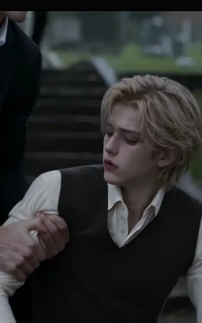 The steadying grip — a light-blond man in a cream collar shirt and black knit vest, head turned aside, dazed and low, his arm held fast by a dark-suited hand and jaw at frame edge, dusk stone steps behind (ep7; intimacy-adjacent frame as aired, not amplified — support context, no violence in frame)