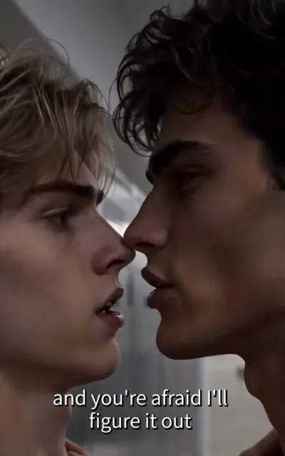 Nose to nose — a light golden-brown-curled young man and a dark-curled young man a breath apart, eyes locked, lips parted, the soft-featured one looking up, the other gazing down, cold indoor light blurred behind, the caption and you're afraid I'll figure it out beneath (ep3; subtitles as aired; HERO frame — intimacy-adjacent frame as aired, not amplified)