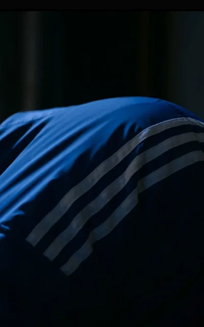The shoulder-to-shoulder walk-off — two number-10s leaving the pitch together, striped trim along one shoulder, the stands emptying behind (ep7; atmosphere beat; brand-pattern kept as aired — striped trim described generically)