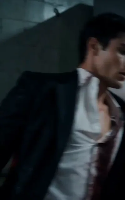 Frame ep01-f00 from episode 1 — Mateo bloodied in the clinic hallway (ep1; subtitles as aired — Save me or we die together.)