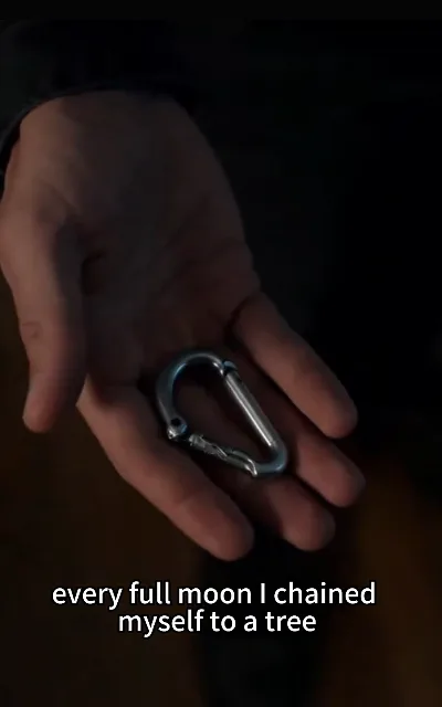 The premise’s core line in close frame — "every full moon I chained myself to a tree" — a hand and a metal carabiner in low light, the wolf’s own discipline staged exactly as shot (ep3, subtitles as aired)