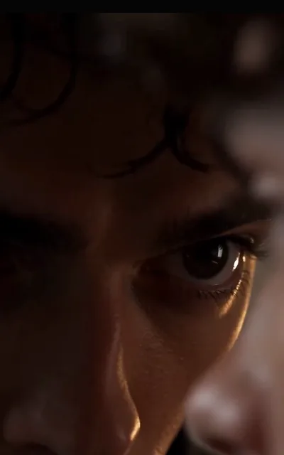 An extreme close-up lit from the side: one dark eye, lashes defined, a blurred foreground edge — everything else swallowed by shadow, staged exactly as shot (ep5)