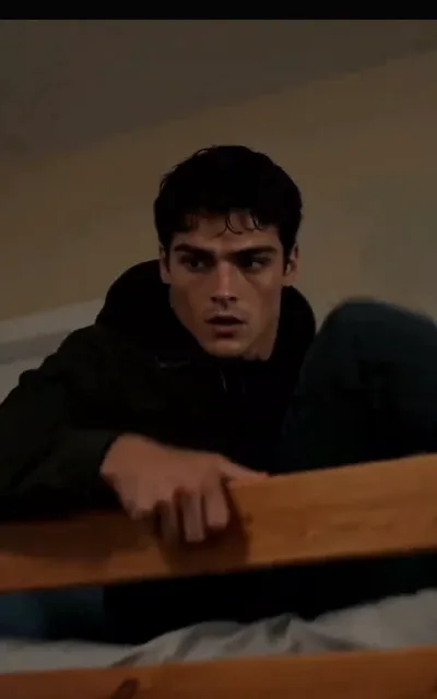 Kael seen from above on the bunk bed — the dorm’s geometry framing the roommate who sleeps a few feet away (ep6)