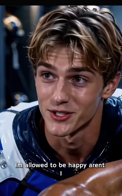 Luca close in under the lights — light golden-brown curls, the small mole near the corner of his mouth, eyes carrying the question — "Im allowed to be happy arent I" (ep1, subtitles as aired; line wrapped over two lines in frame)