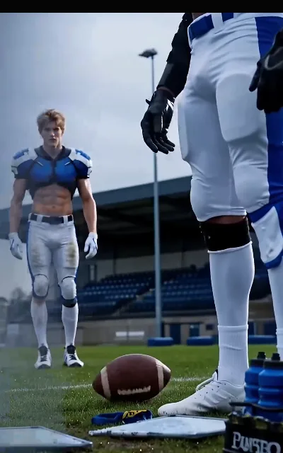 The training field under a gray sky — the receiver shirtless in blue-and-white shoulder pads walking back toward camp, a ball and bottles staged on the turf, the stands empty and waiting (ep5)