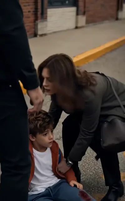 An accident on the street — Leo with a scraped knee, his mother crouched close, the worry doing the talking (ep3; kept restrained, no injury detail)