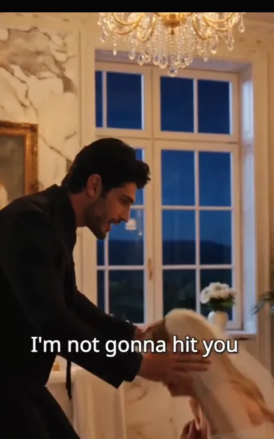 Under the chandelier — her flinch caught mid-motion, his raised hand stilled into an open, placating gesture, the caption beneath reading “I'm not gonna hit you” (ep5; violence-context frame as aired, not amplified — domestic-violence hint kept at caption level, the line is NOT used as a quote card)
