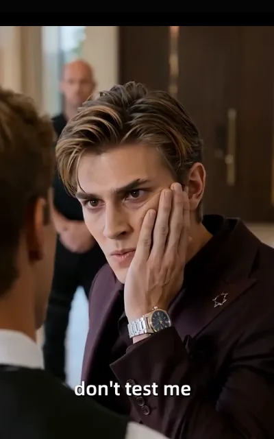 The warning lean-in — a golden-brown-haired man close over the protagonist's shoulder, jaw set, the caption “don't test me” beneath (ep2; subtitles as aired)