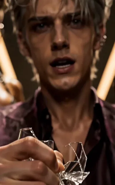 The shattered glass — a broken wine glass in the foreground, the silver-haired man blurred behind it; the scene turns without anyone raising a voice, and he stays unnamed (ep5)