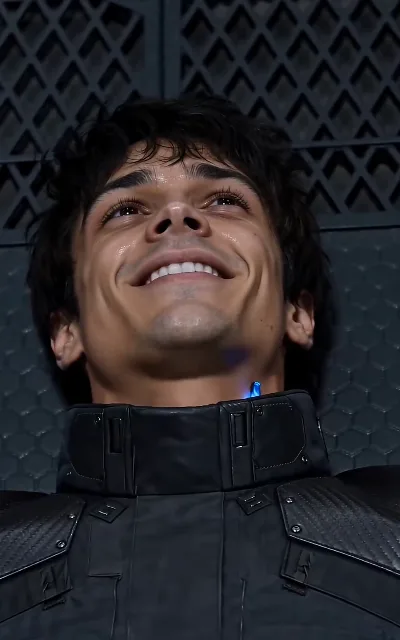 The other side of the smirk — Elliot's head tipped back, actually smiling, the blue glow at his collar: the contract's first honest moment (ep6)