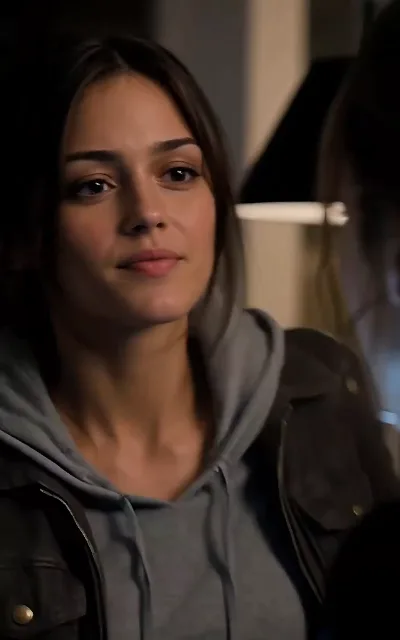 The quiet between crises — a soft-lit close-up, faint smile, eyes somewhere off-frame (ep6)