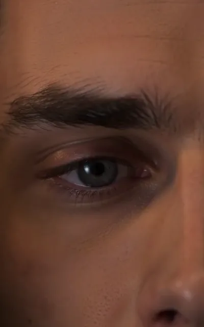 The half-profile — the right half of the male lead's face in tight close-up, eye steady, warm low light (ep6; atmosphere beat — portrait frame)