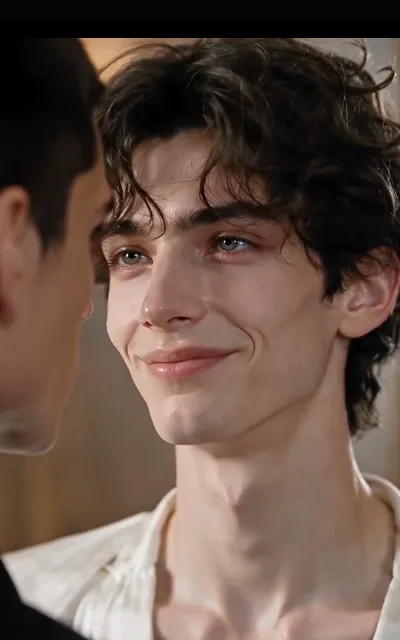 The soft look — curls loose, eyes warm on the person beside him, ivory shirt open at the throat, only an ear and a jawline in the opposite corner (ep2; atmosphere beat)