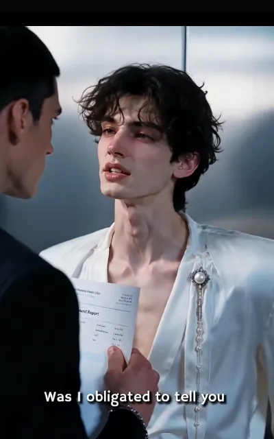 Elias against the dark — ivory V-neck, pearl brooch, chin up while a Report page is held in his face from the edge of frame — “Was I obligated to tell you” (ep7; subtitles as aired; Elias line-anchor frame)