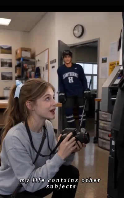 The studio surprise — Piper looking up from her camera as a full hockey kit fills the doorway behind her (ep9)