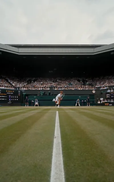 Low angle on the serve — the fair-haired player in all white mid-motion, the speed gun reading 117mph: the opening set of the rivalry in a single frame (ep1)
